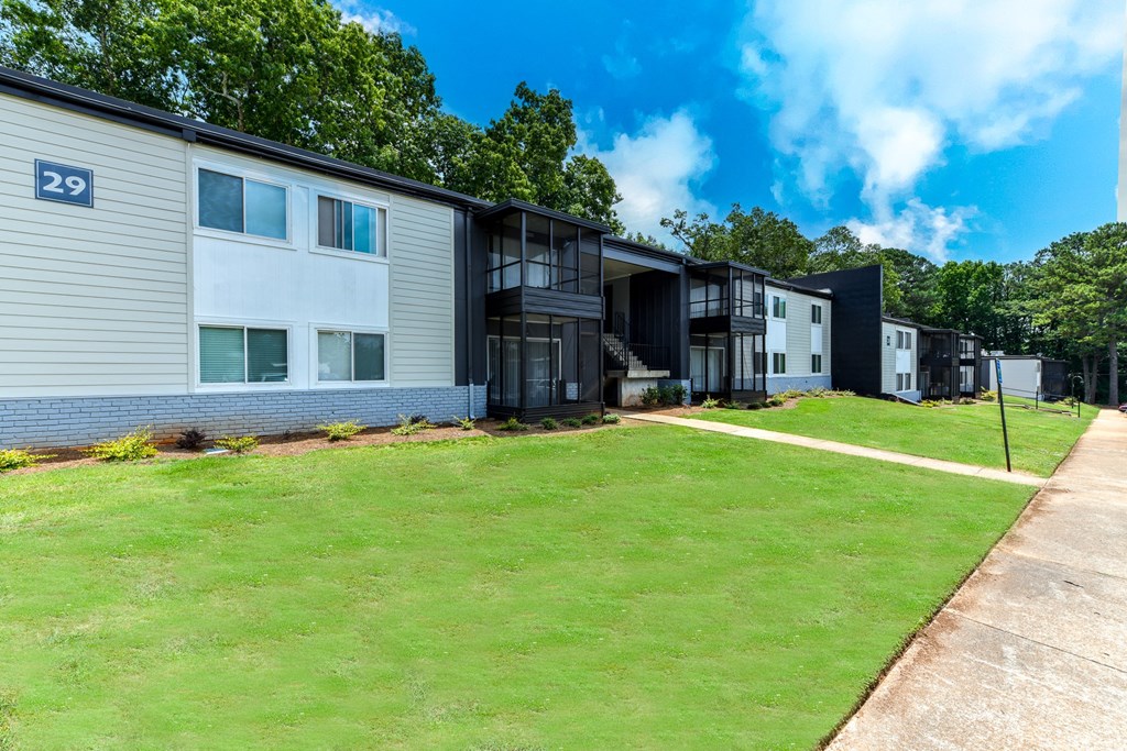 a row of apartment buildings with a green lawn in front of them