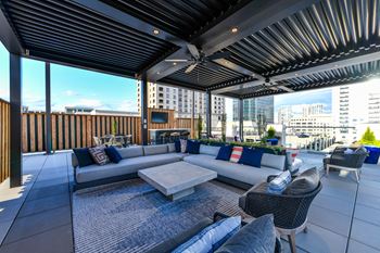 an outdoor living area with couches and chairs and a tv on the wall