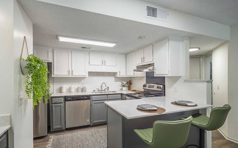 A kitchen with a green chair and a plant hanging on the wall.