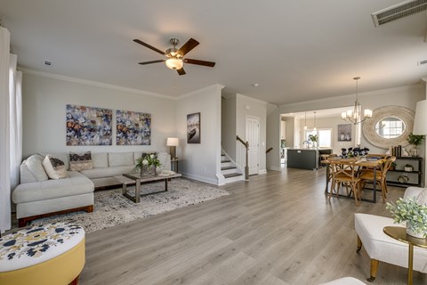 A living room with a couch, coffee table, and a dining table.
