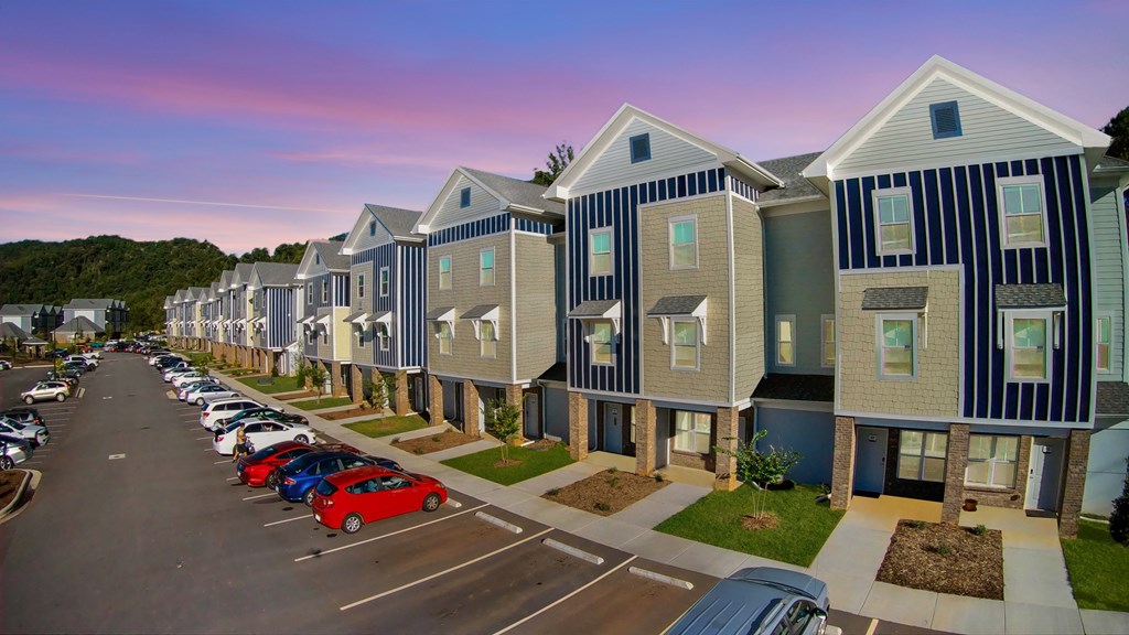 A long row of houses with cars parked in front.