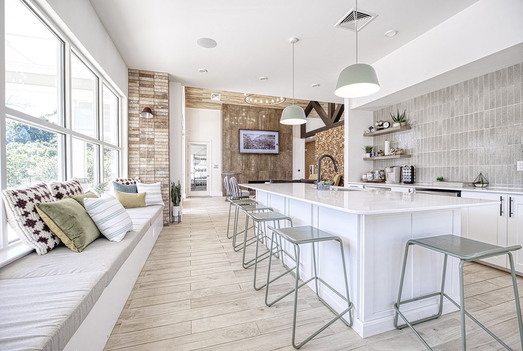A kitchen with a white counter and a white couch with pillows.