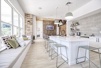 A kitchen with a white counter and a white couch with pillows.