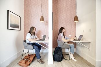 Two people working on laptops in a room.