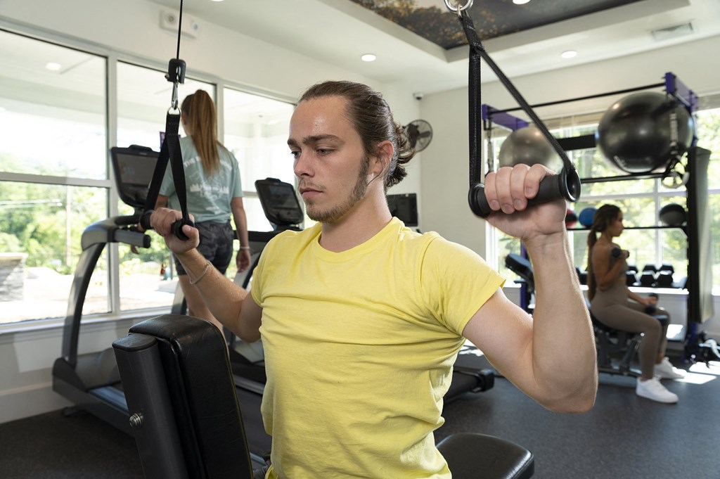 A man in a yellow shirt is using a gym machine.