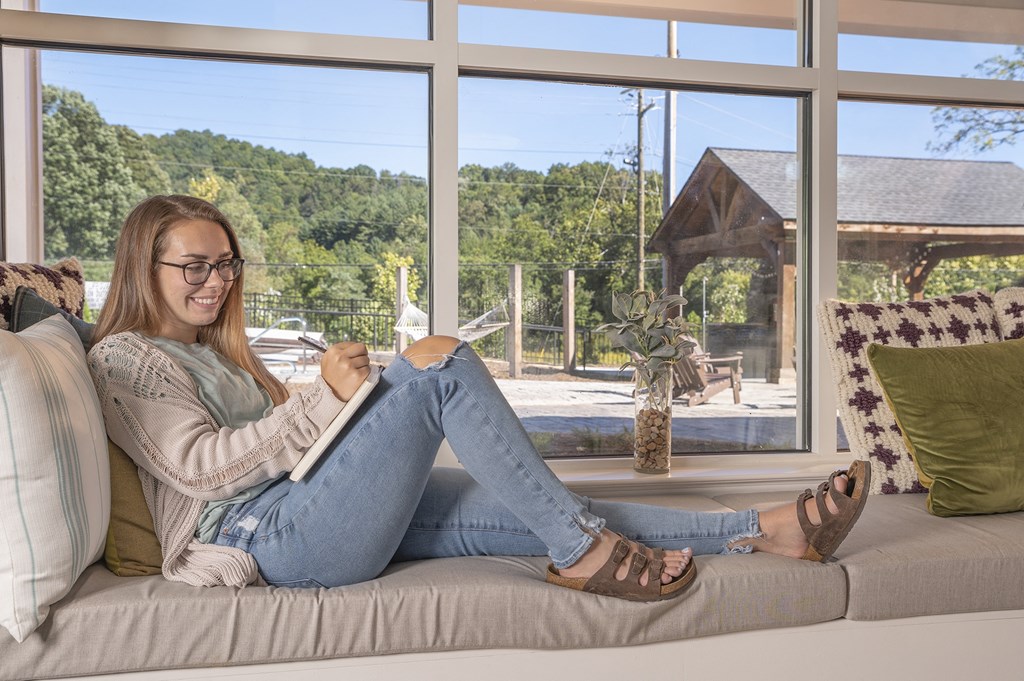 A woman is sitting on a couch reading a book.