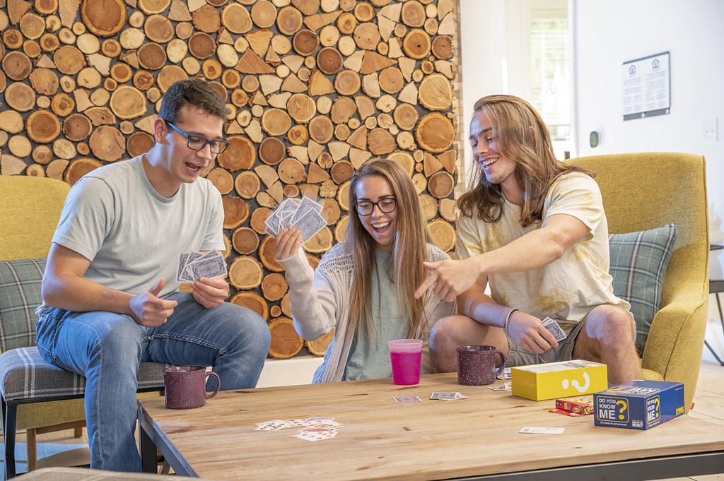 Three people playing a card game on a wooden table.