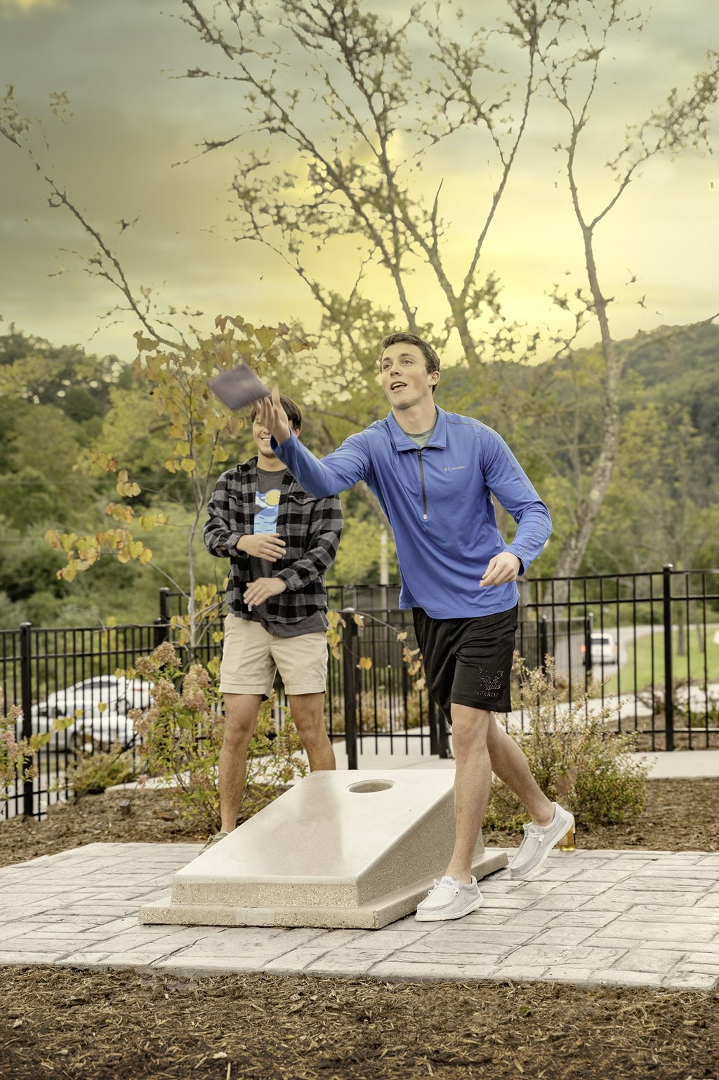 A man in a blue shirt and white shorts is standing on a concrete structure.