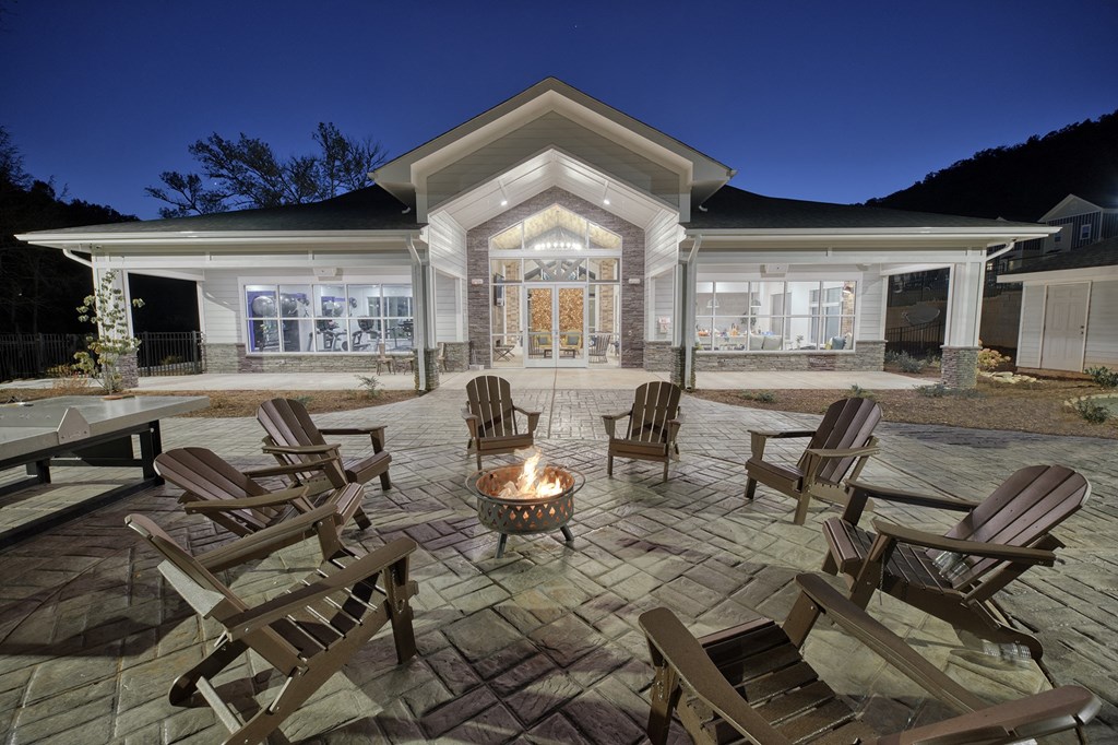 A patio with chairs and a fire pit in front of a house.