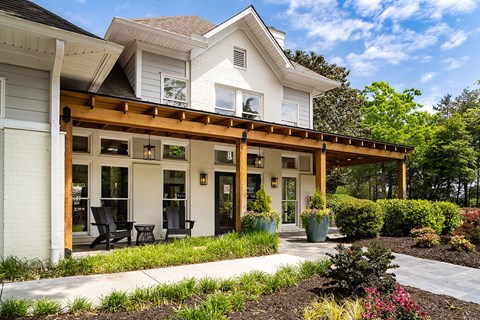 A white house with a wooden porch and a black table and chairs.