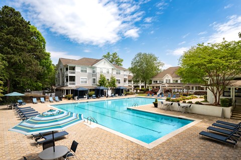 A large swimming pool surrounded by lounge chairs and umbrellas.