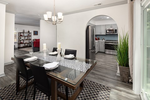 A modern dining room with a glass table and chairs.