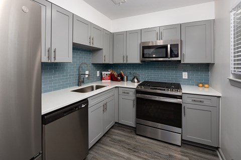 A kitchen with a stainless steel refrigerator, microwave, oven, and dishwasher.