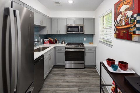 A modern kitchen with a refrigerator, microwave, oven, and dishwasher.