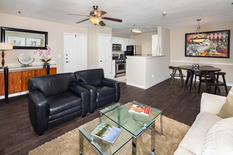 A black leather couch sits in a living room with a glass coffee table in front of it.