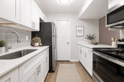 A kitchen with white cabinets and a black refrigerator.