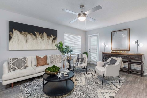A living room with a white couch, a coffee table, and a large painting on the wall.