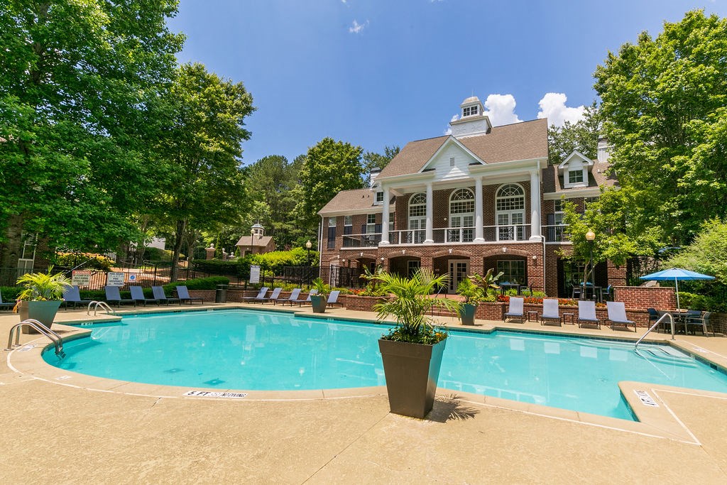 a swimming pool with chairs around it in front of a house