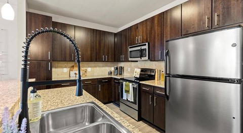 A kitchen with a stainless steel refrigerator and a sink with a faucet.
