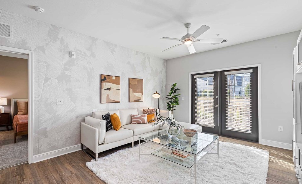 A living room with a white couch and a glass coffee table.