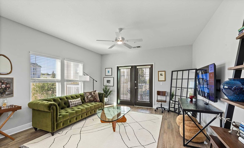A living room with a green couch and a white rug.