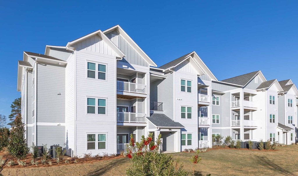 A large white residential building with multiple balconies and windows.