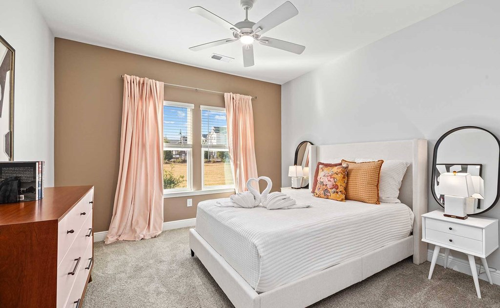 A bedroom with a large bed, a dresser, and a ceiling fan.