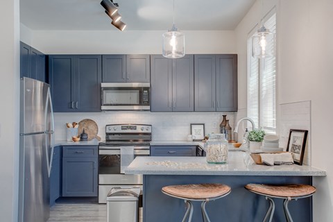 a kitchen with blue cabinets and a counter with three stools