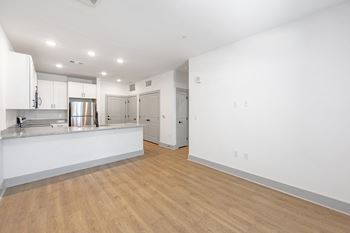 a living room and kitchen with white walls and wood flooring