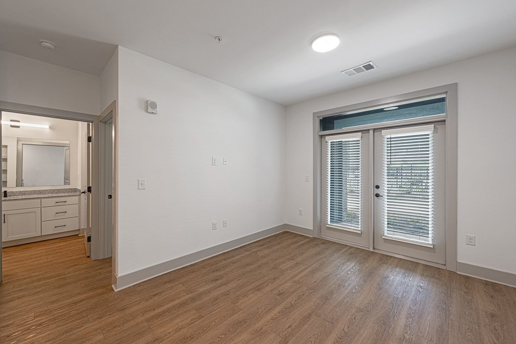 an empty living room with white walls and a door to a bathroom