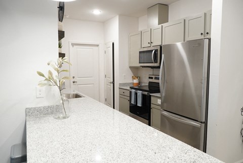 A kitchen with a granite counter top and stainless steel appliances.