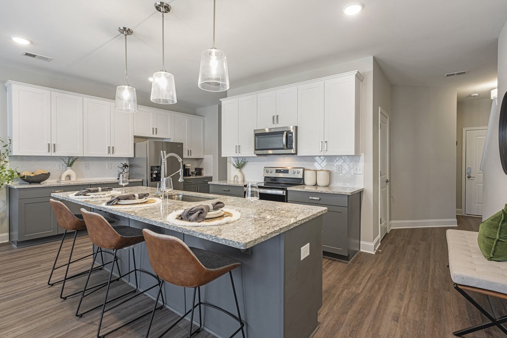 a kitchen with white cabinets and a marble counter top