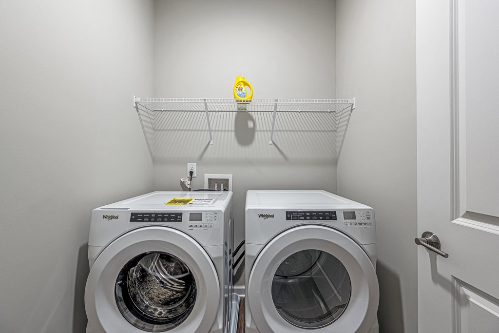 two washing machines in a laundry room with a shelf above them
