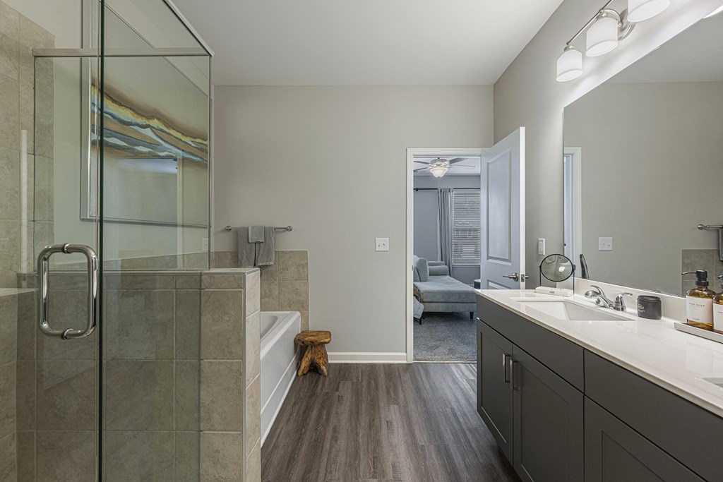 a bathroom with a glass shower and a sink and a tub