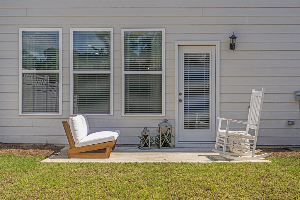 a white rocking chair on a patio in front of a white house