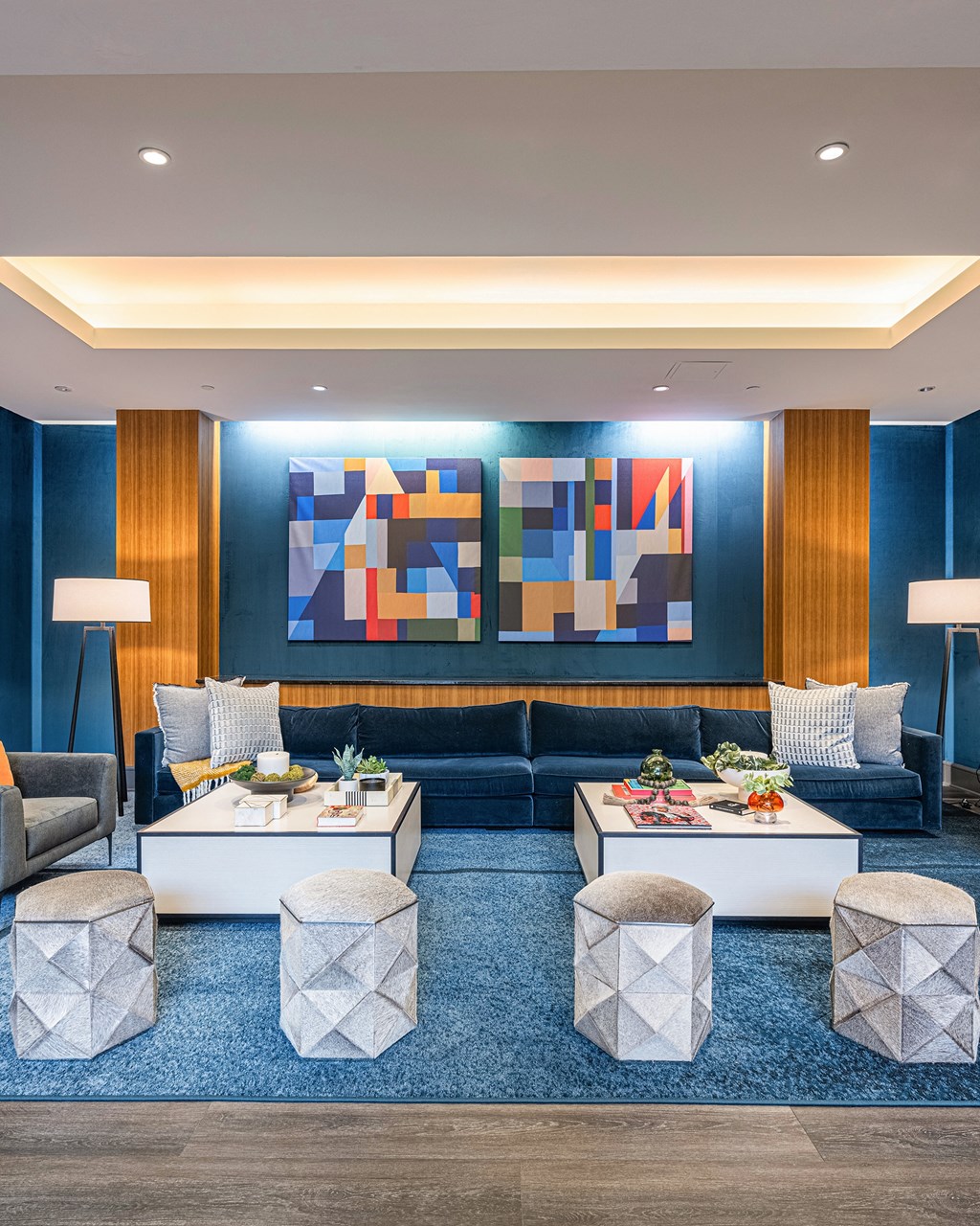 a living room with blue walls and furniture and a colorful wall art