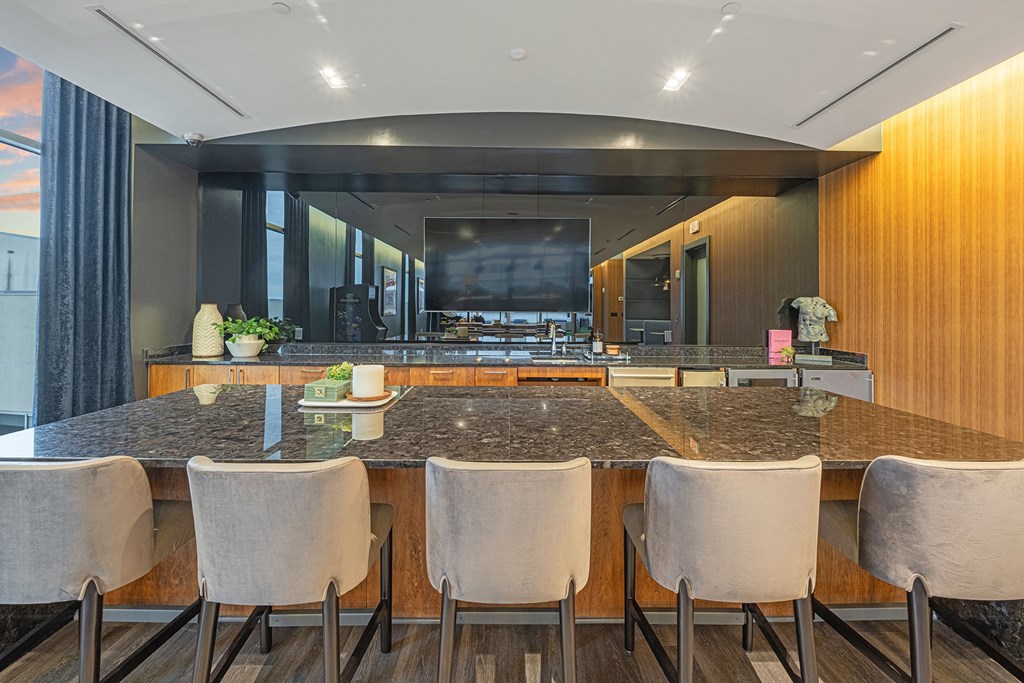 a large kitchen with marble counter tops and a long bar with chairs