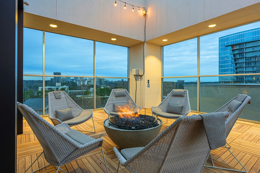 a patio with a fire pit and chairs on a balcony with large windows