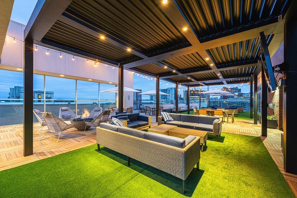 a roof top terrace with couches and chairs and a view of the city