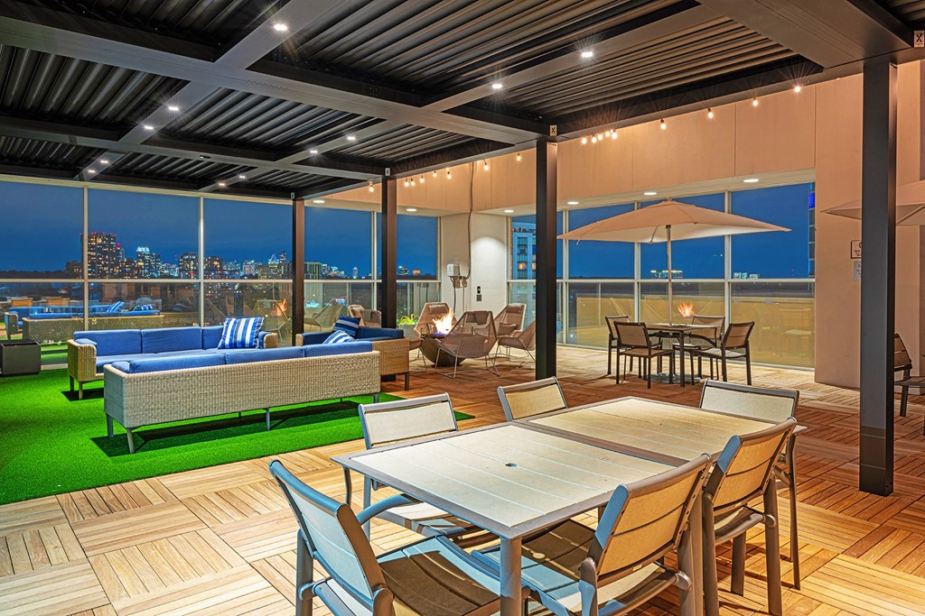 a patio with tables and chairs and a view of a city at night