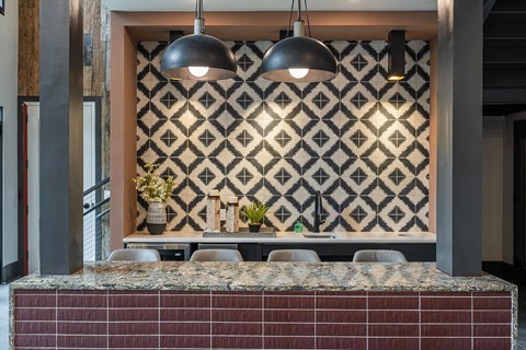 a kitchen with a counter and chairs and a patterned wall