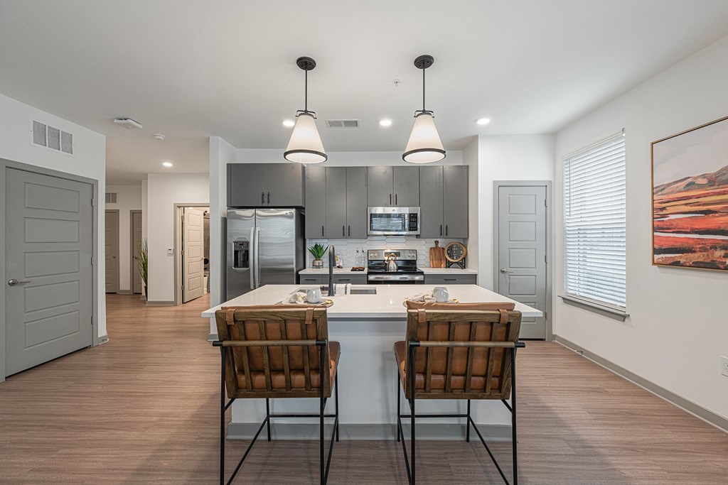 an open kitchen with a large island with two chairs in front of it