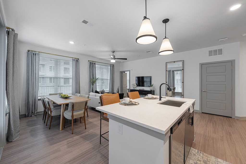 an open kitchen and living room with a dining room table and chairs and an island