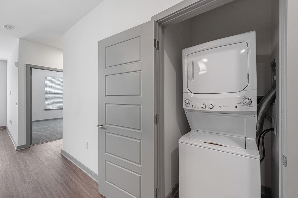 a laundry room with a washer and dryer and a door to a hallway