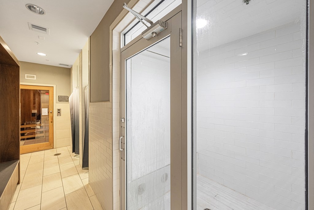 a glass shower door in a bathroom with a tiled floor