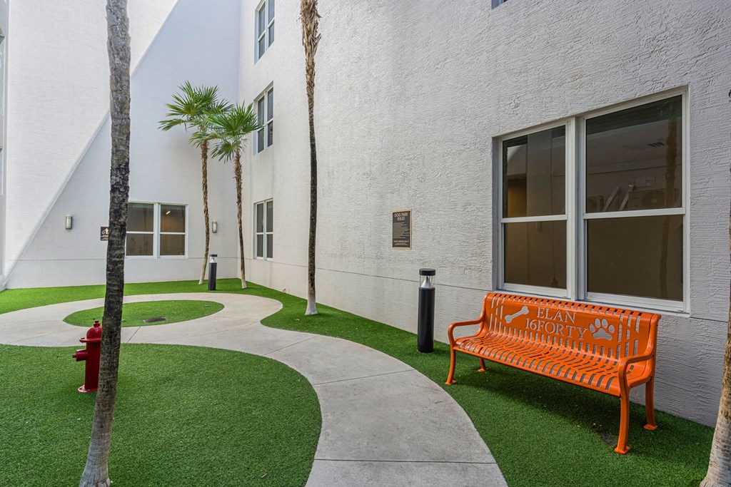 an orange bench in front of a white building with palm trees