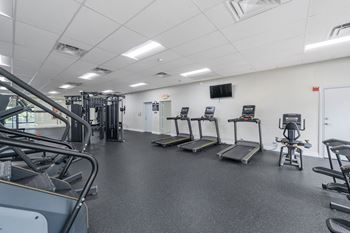 a gym with cardio equipment and weights on the floor