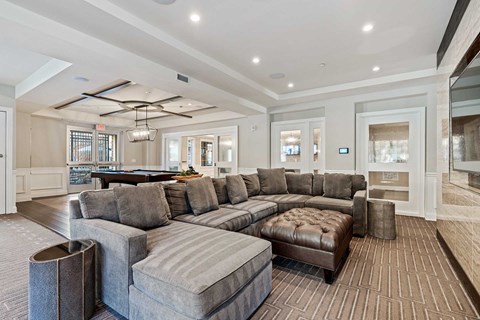 A large grey sectional sofa with a chaise lounge and ottoman in a spacious living room.