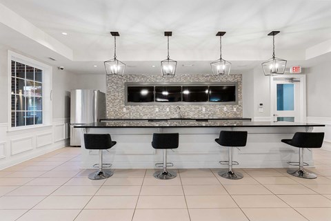 A modern kitchen with a bar area and black stools.