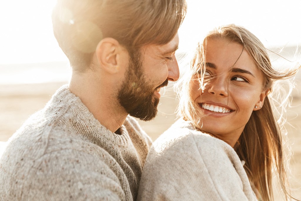 a man and a woman smiling at each other on the beach
